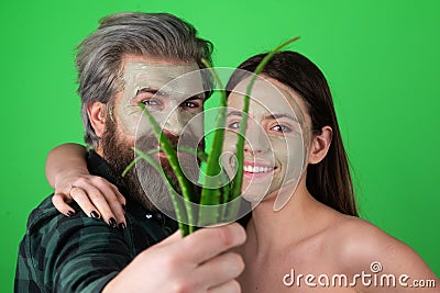 Facial green mask for fun couple. Funny couple getting facial care with aloe vera. Beautician is making facial mask on Stock Photo