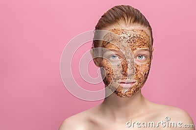 Facial skin scrub Coffee grounds mask on the face of a beautiful young woman Organic natural cosmetology Pink studio Stock Photo