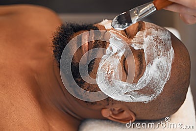 Facial, skincare and relax with black man in spa for beauty, luxury and mud mask. Wellness, therapy and health with male Stock Photo