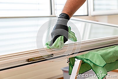Facility management cleaner cleaning a window and window frame with green micro fiber cloths Stock Photo