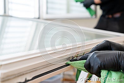 Facility management cleaners cleaning a window and window frame with green micro fiber cloths Stock Photo