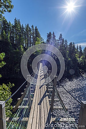 Facing to the sun, the Suspended bridge is to cross the water course between Jyravanjarvi and Ala-Juumajarvi lakes in Oulanka Stock Photo