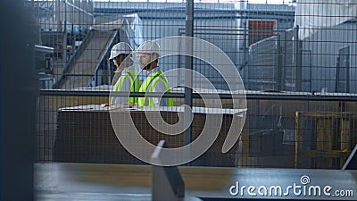 Factory supervisors inspecting warehouse analysing production process talking Stock Photo