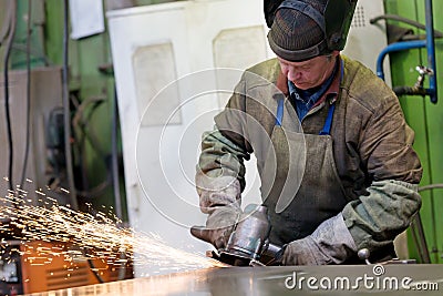 Factory welder worker grinding steel sheet at workshop Stock Photo