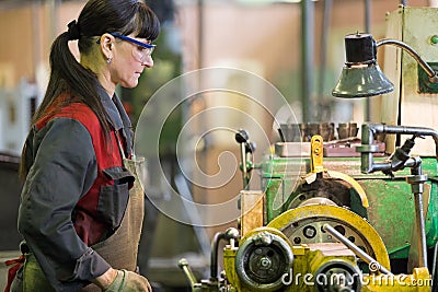 Factory woman turner working at workshop lathe machine Stock Photo