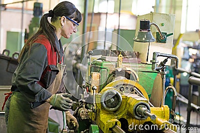 Factory woman turner working on workshop lathe machine Stock Photo