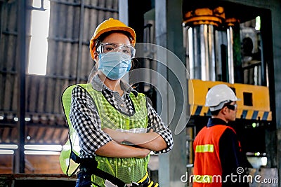Factory woman worker or technician with hygienic mask stand with confident action with her co-worker as background Stock Photo