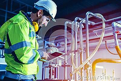 Factory worker engineer working in factory using tablet computer to check maintenance boiler water pipe in factory Stock Photo
