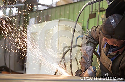 Factory worker grinding steel sheet with flying sparks Stock Photo