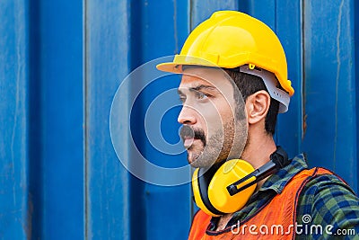 Factory worker man in hard hat and noise reduction ear muffs with containers box background Stock Photo