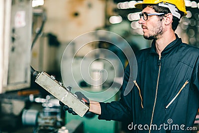 Factory worker man intend to operate the machine, high skill labor work industry with safety clothes Stock Photo