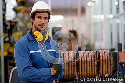 Factory worker man stand in front of copper tube or pipe hold wrench and action of confident in workplace. Concept of good Stock Photo