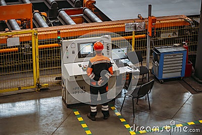 Factory worker monitoring CNC machine in metalworking workshop Editorial Stock Photo
