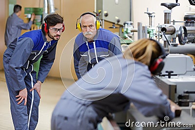 Factory workers wearing ear defenders examining machinery Stock Photo