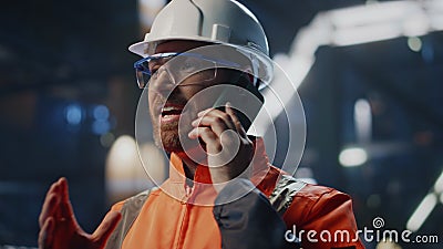 Factory workman talking mobile phone standing at industrial facility close up. Stock Photo