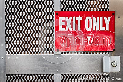 Faded worn exit only sign on a steel gate Stock Photo