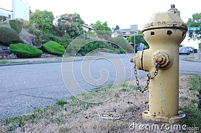 Faded yellow fire hydrant in a quiet suburban street Stock Photo