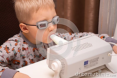 A fair-haired boy in pajamas undergoes prevention of viruses and diseases at home using a quartz germicidal irradiator. Disease Stock Photo