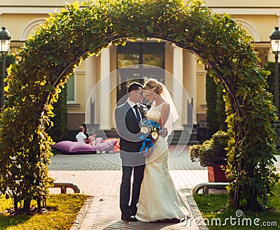 fair-haired bride with a bouquet of flowers in her hands and her fiance are standing near a natural arch Stock Photo