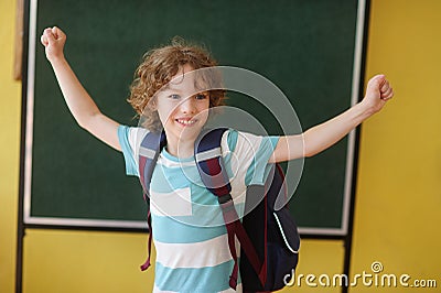 The fair-haired curly school student stand against a blackboard. Stock Photo