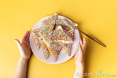 Fairy bread in hand. The famous traditional Australian food Fairy Bread on a yellow background Stock Photo
