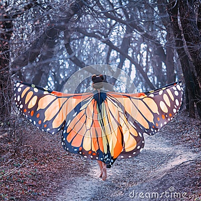 Fairy tale about butterfly, mysterious story of girl with red hair and big light orange wings, lady walks barefoot along Stock Photo