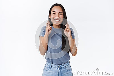 Faithful excited smiling asian woman making wish, cross fingers good luck, look determined camera, believe dreams do Stock Photo