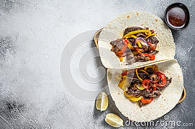 Fajitas with beef meat stripes, colored bell pepper and onions, served with tortillas and salsa. White background. Top view. Copy Stock Photo