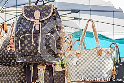 Fake high-end famous designer purses and backpacks for sale at a local outdoor flea market in Ventimiglia, Italy Editorial Stock Photo