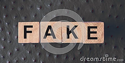 FAKE word written in wooden blocks on red leather. Fake or real news, myth or true concept Stock Photo