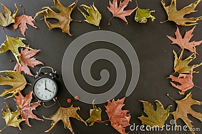 Fall Back, Daylight Saving Time. Black clock and autumn leaves frame Stock Photo