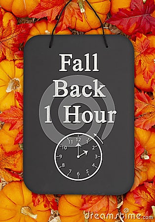 Fall Back 1 hour time change message on a chalkboard sign on pumpkins Stock Photo