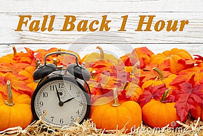 Fall Back 1 hour time change message with a retro alarm clock with pumpkins and fall leaves Stock Photo