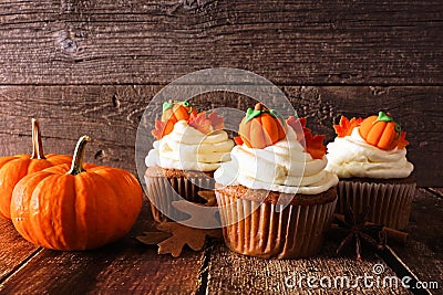 Fall pumpkin spice cupcakes with creamy frosting close up against wood Stock Photo