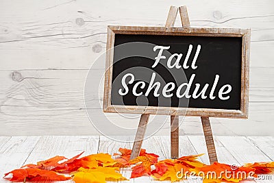 Fall Schedule sign on standing chalkboard on wood with fall leaves Stock Photo