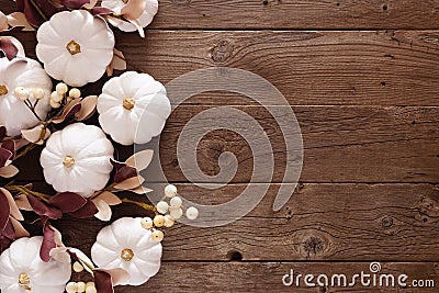 Fall side border of white pumpkins, berries and dusty red leaves against a rustic wood background Stock Photo