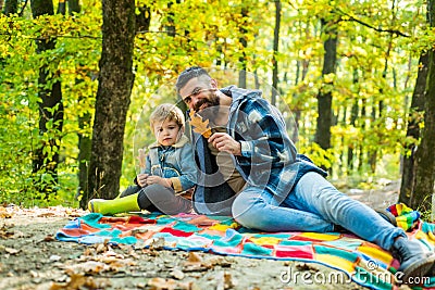 Fallen leaves. Hipster bearded dad with cute son spend time together in forest. Family time. Family leisure. Brutal Stock Photo