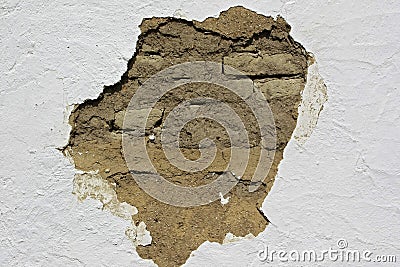 Fallen white platers reveals old mud brick on a country house. Stock Photo