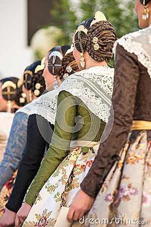 Falleras seen from behind. Dresses with floral designs and typical hairstyle of the fallas with their jewels Editorial Stock Photo