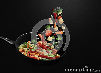 Falling sliced vegetable mix on a frying pan. Flying down frozen vegetables on a black background. Natural organic food. Copy Stock Photo