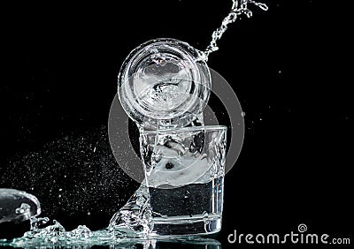 Falling small glasses and spilling water on a black background Stock Photo