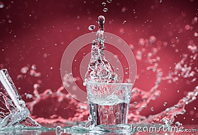 Falling small glasses and spilling water on a blue background Stock Photo