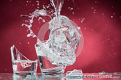 Falling small glasses and spilling water on a blue background Stock Photo