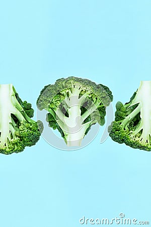 Falling three soaring close-up green broccoli slices on a blue background. Stock Photo