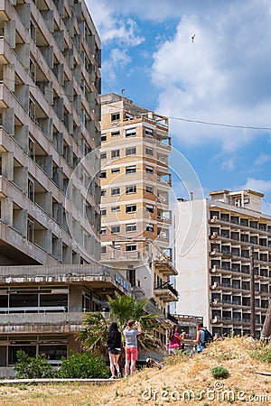 People gaze at the abandoned hotels by the beach of the ghost city of Varosha Famagusta on a sunny day Editorial Stock Photo