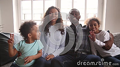 Famiglia africana che si siede sulle mani d'ondeggiamento dello strato che esaminano macchina fotografica stock footage Famiglia africana che si siede sulle mani d'ondeggiamento dello strato che esaminano macchina fotografica stock footage