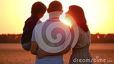 Famiglia felice: papà, mamma e figlio piccolo amano la natura e il tramonto Un padre tiene il figlio tra le braccia, una donna ba Famiglia felice: papà, mamma e figlio piccolo amano la natura e il tramonto Un padre tiene il figlio tra le braccia, una donna ba