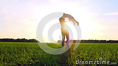 Familia feliz que juega la naturaleza en el parque en la puesta del sol El padre detiene a su hijo al lado de los brazos y da vue Familia feliz que juega la naturaleza en el parque en la puesta del sol El padre detiene a su hijo al lado de los brazos y da vue
