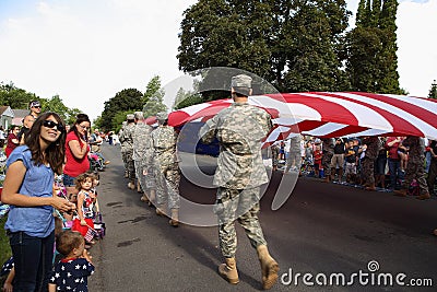 Families watch the US flag go by at a fourth of July parade. Editorial Stock Photo