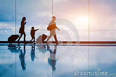 Family at airport travelling with young child and luggage walking to departure gate, girl pointing at airplanes through window, Editorial Stock Photo